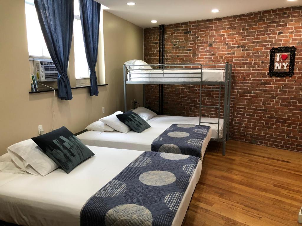 Ce lit se trouve dans un dortoir doté de 2 lits superposés et d'un mur en briques. dans l'établissement Studios Midtown Manhattan, à New York