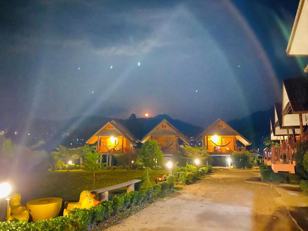 拜縣的住宿－拜縣微笑度假村，一群晚上在天空下有彩虹的房子