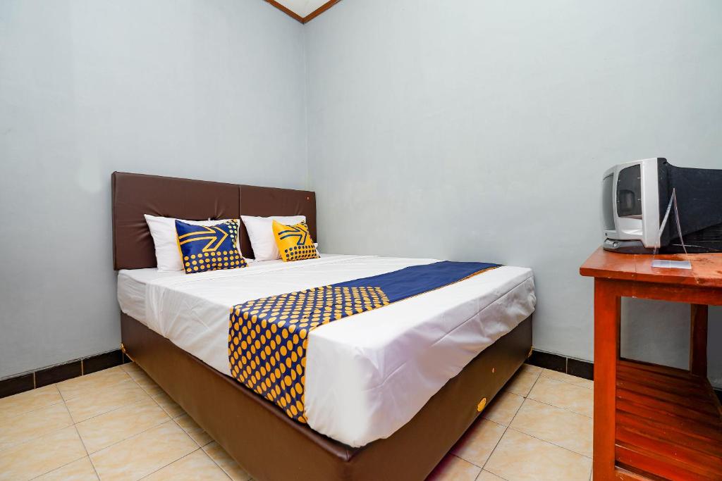 een bed met gele en blauwe kussens in een slaapkamer bij SPOT ON 2821 Griya Kawula Syariah in Solo