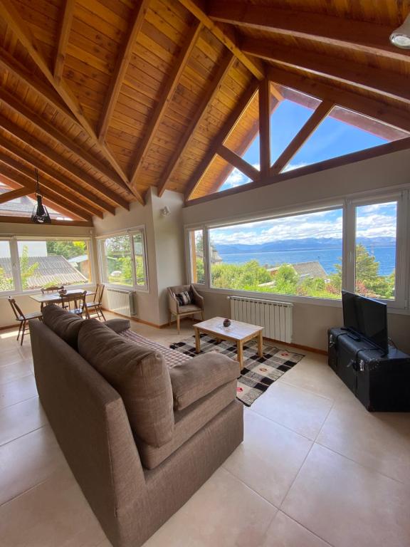 a living room with a couch and a tv and windows at Andalue in San Carlos de Bariloche