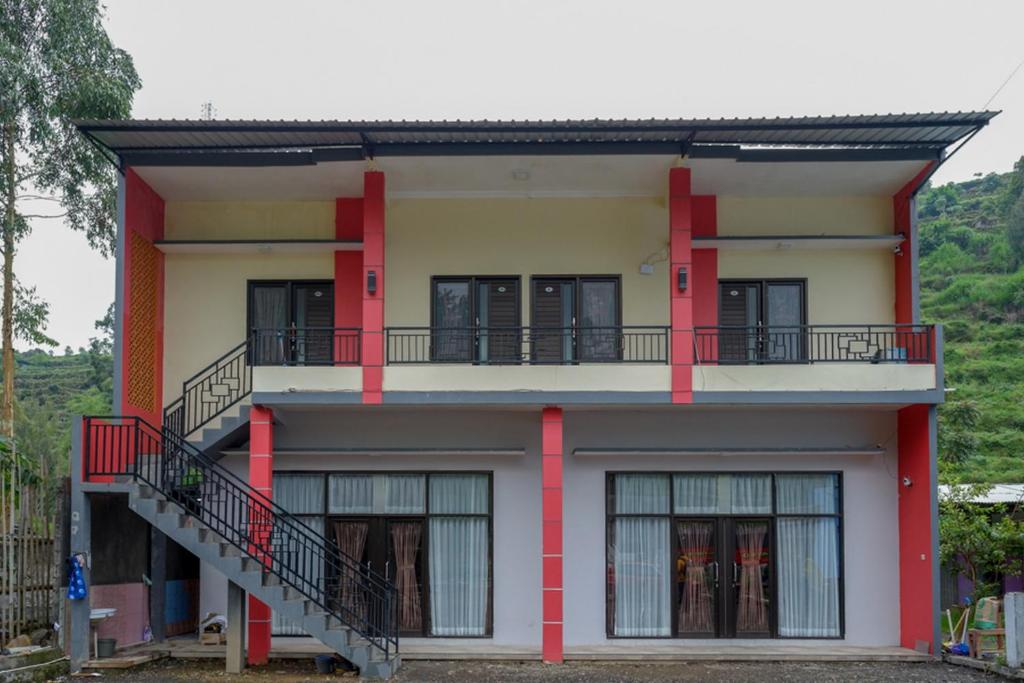 RedDoorz @ Gerbang Dieng Plateau Area في وونوسوبو: منزل به اعمده حمراء وبلكونه