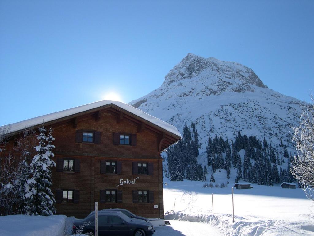 レッヒにあるHaus Gstüatの山を背景にした雪に覆われた建物