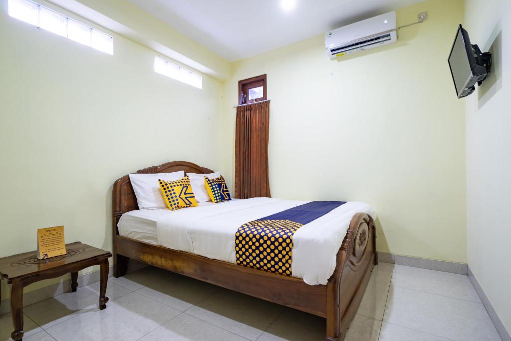 een slaapkamer met een bed en een tv aan de muur bij SPOT ON 2881 Nabila Homestay in Yogyakarta