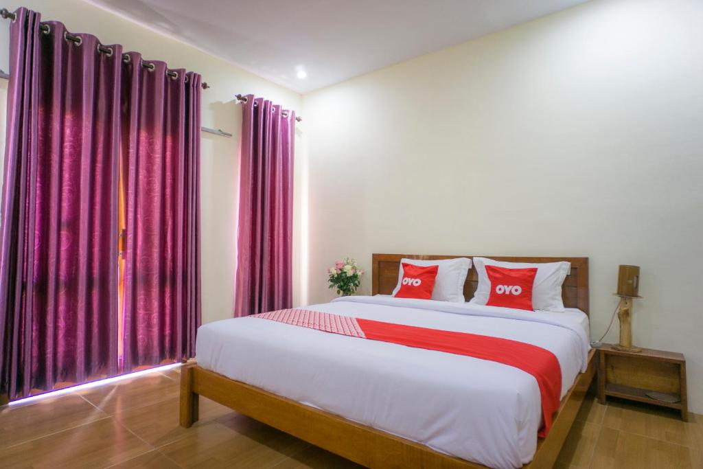 a bedroom with a large bed with red pillows at OYO 1696 Sapo Rumbia in Berastagi