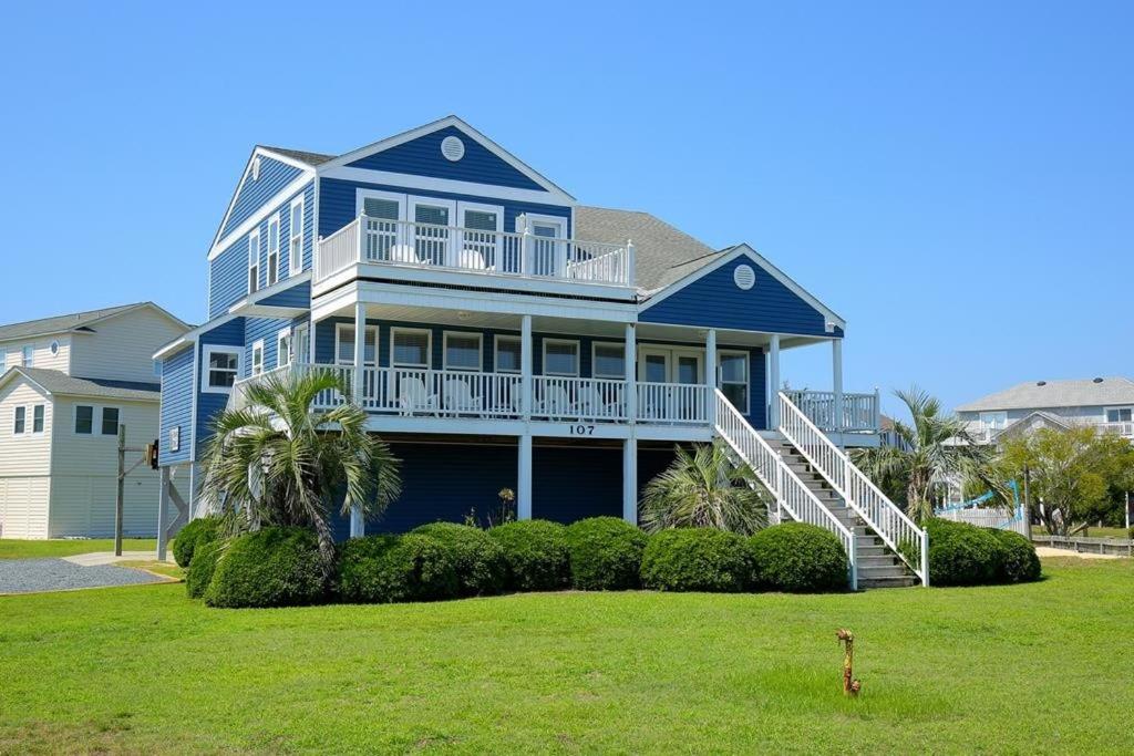 a large blue house with a porch and a lawn at Long Grass in Holden Beach