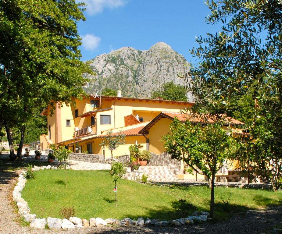 a yellow house with a mountain in the background at Verdeblu Country Hotel in San Giovanni a Piro