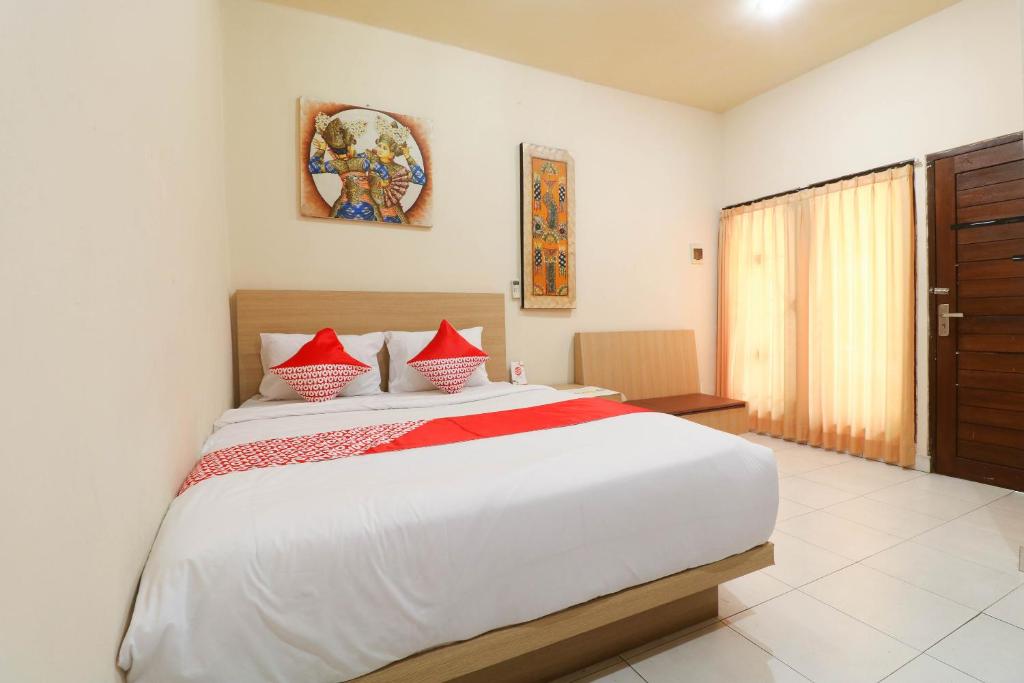 a bedroom with a large white bed with red pillows at OYO 2581 Ketut Smile in Denpasar