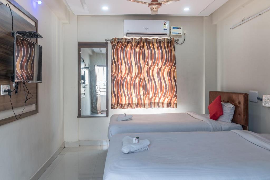 2 łóżka w małym pokoju z oknem w obiekcie Hotel Renuka w mieście Visakhapatnam