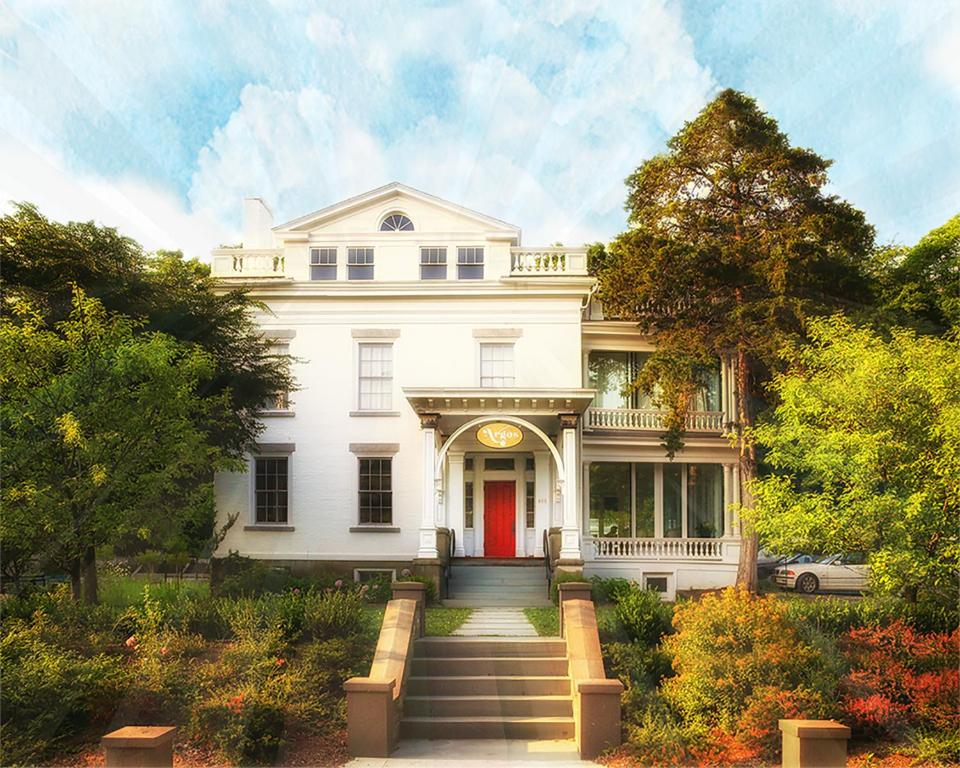 a white house with a red door and stairs at Argos Inn - Ithaca's Boutique Hotel in Ithaca