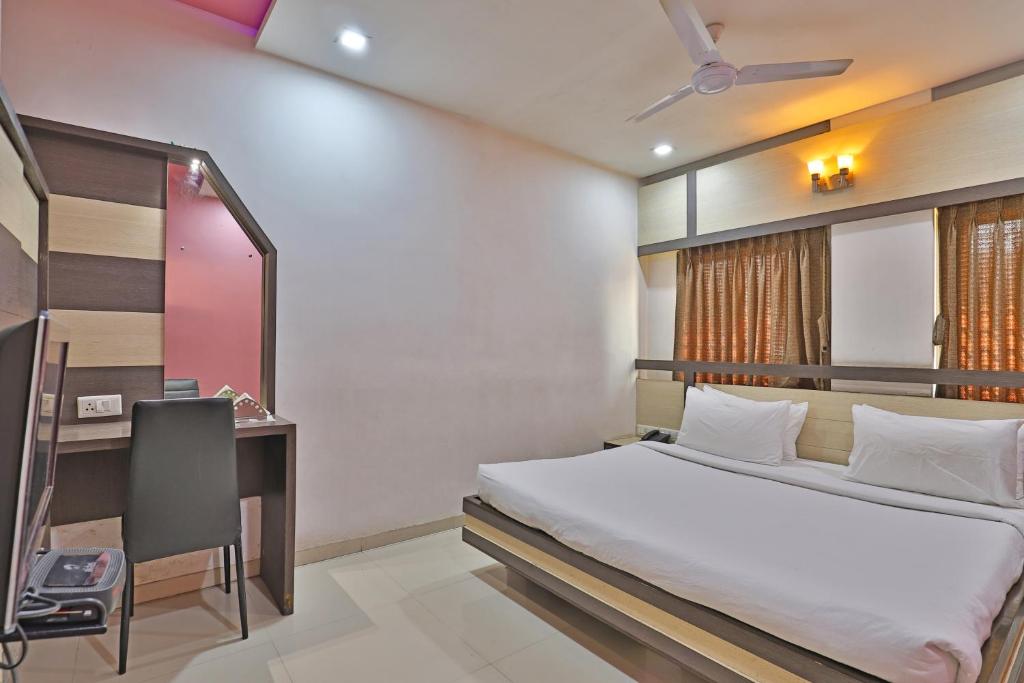 a bedroom with a bed and a desk and a computer at Hotel Merit in Surat