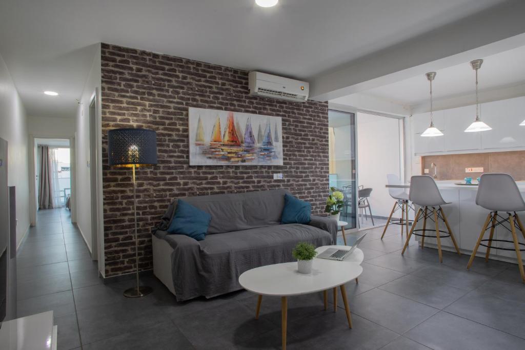 een woonkamer met een bank en een bakstenen muur bij Poseidon Apartment by Michalis in Ayia Napa