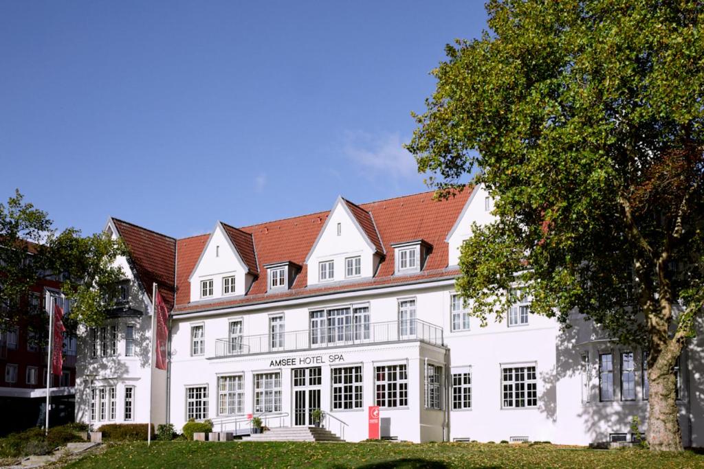 ein großes weißes Gebäude mit rotem Dach in der Unterkunft Spa Hotel Amsee in Waren (Müritz)