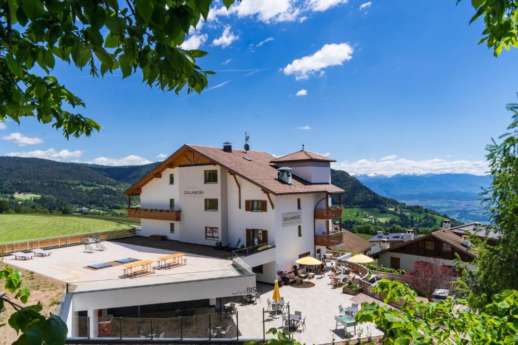 a large white building with a patio and mountains in the background at Pension Schlaneiderhof in Meltina