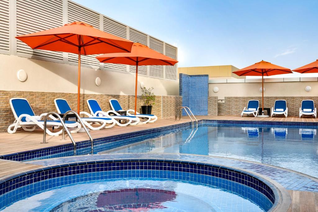 a pool at a hotel with chairs and umbrellas at Ramada by Wyndham Dubai Deira in Dubai
