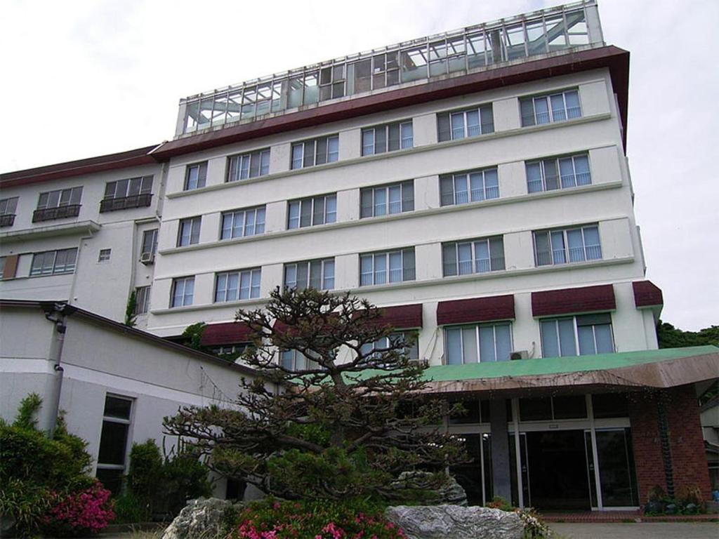 a large white building with a tree in front of it at Suzunami in Toba