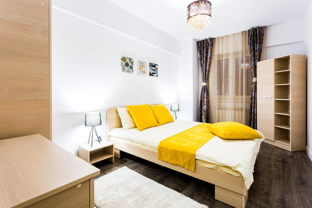 ein Schlafzimmer mit einem Bett mit gelben Kissen in der Unterkunft Unique Hotel Apartments Grand Residence in Iaşi