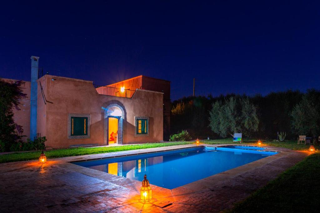 - une piscine en face d'une maison la nuit dans l'établissement Riad Oussari, à Marrakech