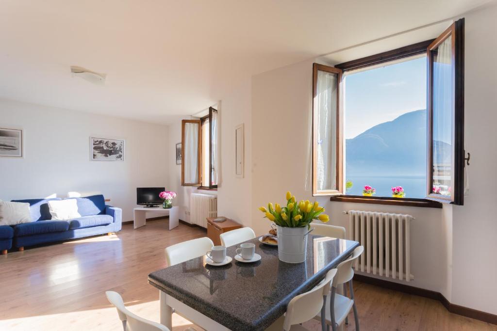 a living room with a table and chairs and a large window at Family Lake Apartment by Rent All Como in Mezzegra