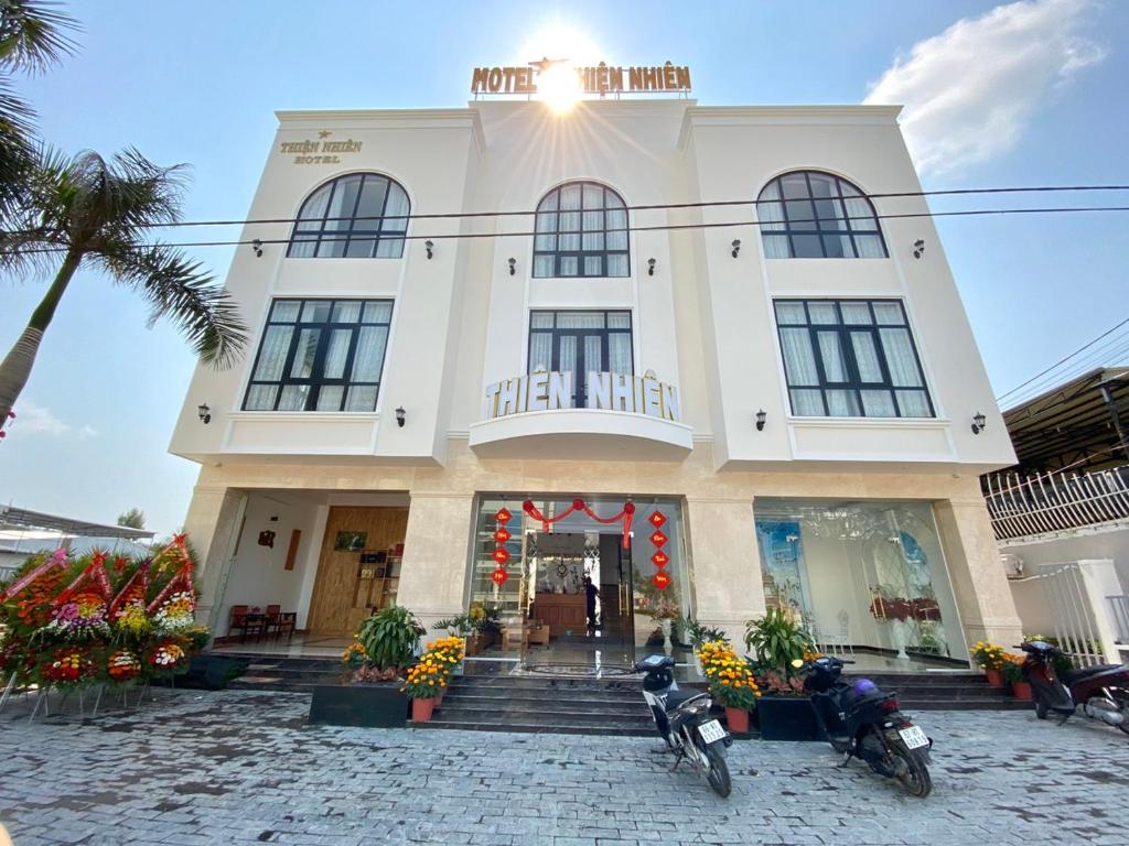 un edificio blanco con motocicletas estacionadas frente a él en Hotel Thiện Nhiên, en Hồng Ngự