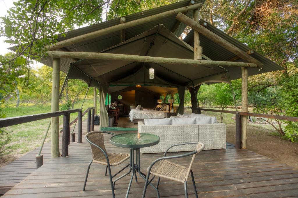 a wooden deck with a couch and a table and chairs at Camp Bethel in Hoedspruit