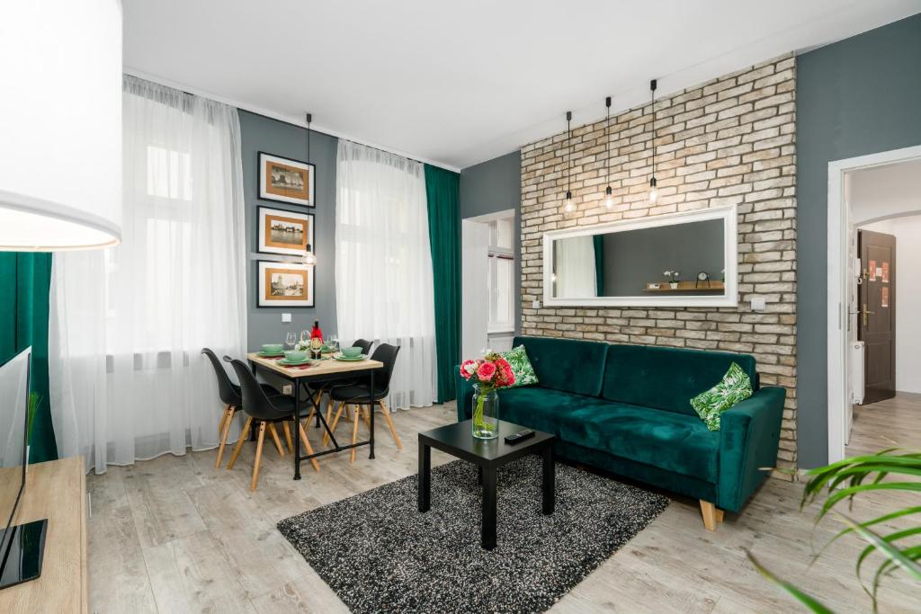 a living room with a green couch and a table at Deluxe Old Town Apartment by Renters in Poznań