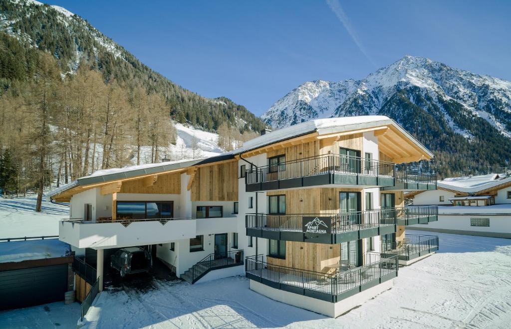 ein Gebäude im Schnee mit Bergen im Hintergrund in der Unterkunft Apart Montagna in Gries