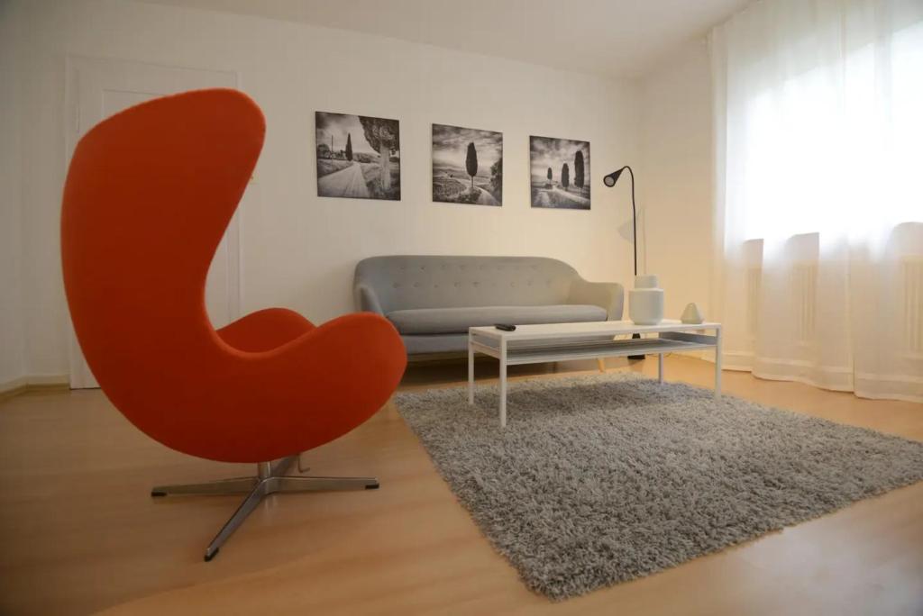 ein Wohnzimmer mit einem roten Stuhl und einem Sofa in der Unterkunft WeinheimResidence in Weinheim
