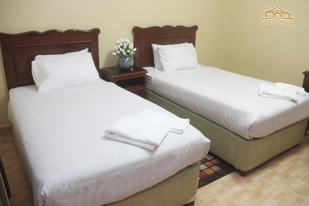 2 camas en una habitación de hotel con sábanas blancas en Orient House Hotel Suites & Apartments بيت الشرق للشقق الفندقية, en Amán