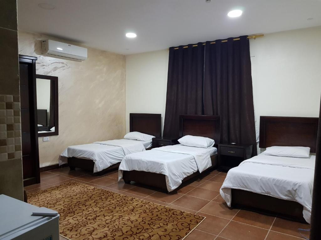 ein Hotelzimmer mit 3 Betten und einem TV in der Unterkunft Siveen Hotel in Amman