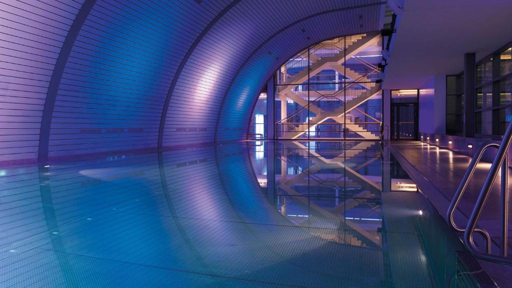 ein Pool in einem Gebäude mit blauen Lichtern in der Unterkunft Aspria Berlin Ku'damm in Berlin