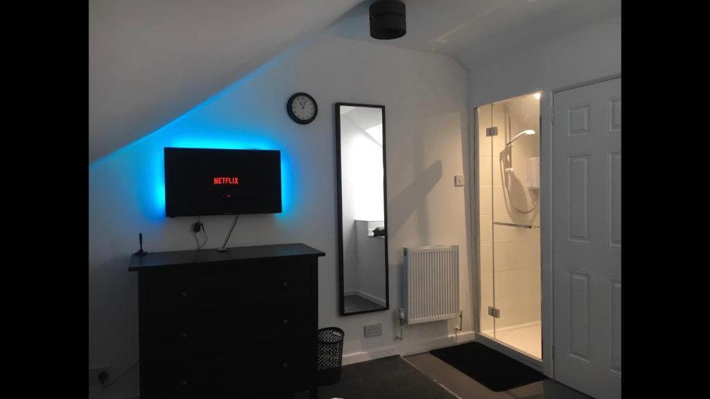 Habitación con TV y reloj en la pared en Scotland Beds, en Dundee