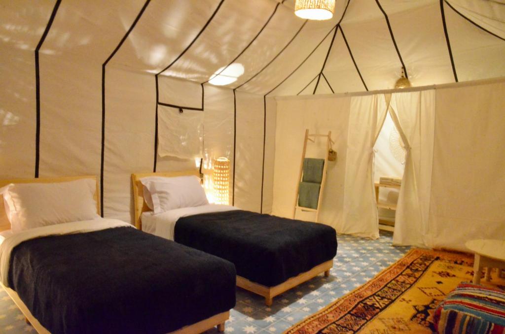 a bedroom with two beds in a tent at Jardin Kotori Luxury Camp in Merzouga