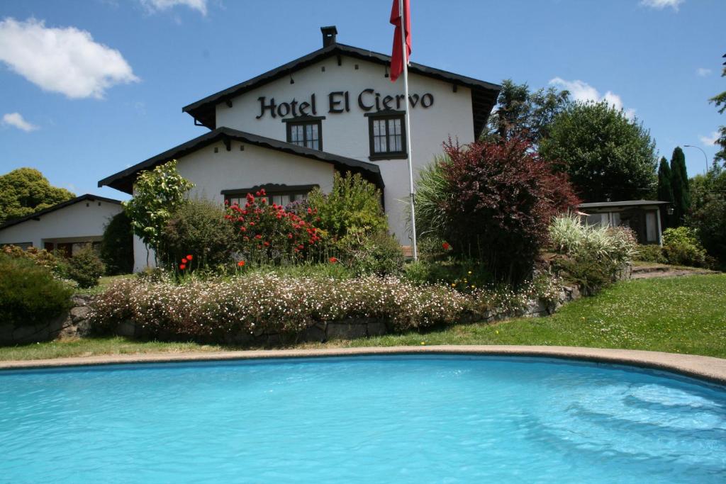 a building with a swimming pool in front of a house at Hotel El Ciervo in Villarrica