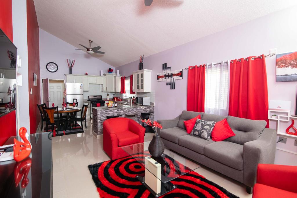 sala de estar con sofá y silla roja en The Oasis II, Caymanas Country Club, en Ellis Caymanas