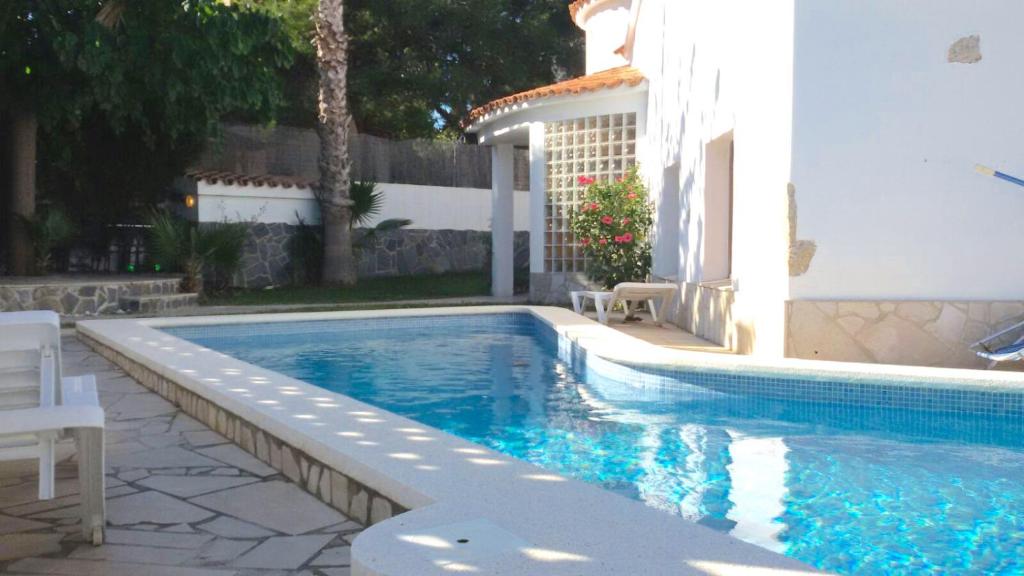 a swimming pool next to a white building at Hauzify I Villa Parc in Hospitalet de l'Infant