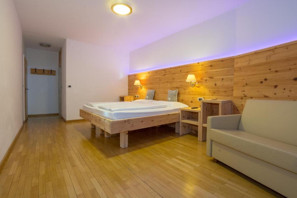 a large room with a large bed and a couch at Hotel Garni Snaltnerhof in Ortisei