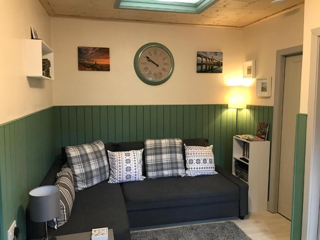 a living room with a couch and a clock on the wall at Apartment/Flat 3 in Menai Bridge