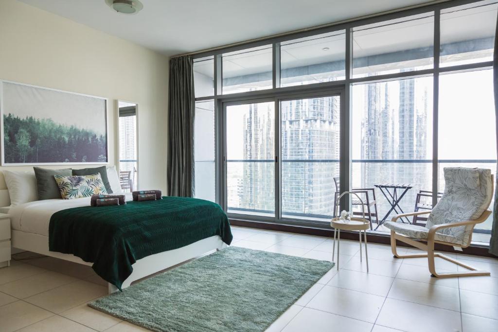 a bedroom with a bed and a couch and windows at HiGuests - Cozy Studio With Panoramic Views on the Lake in Dubai