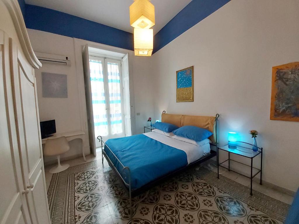 Schlafzimmer mit einem Bett mit blauer Bettwäsche und einem Fenster in der Unterkunft B&B Platamon in Neapel
