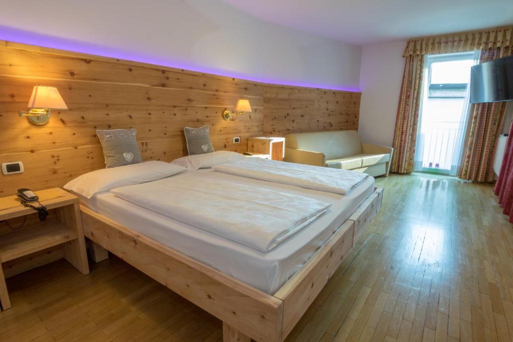 a bedroom with a large bed with a wooden wall at Hotel Garni Snaltnerhof in Ortisei