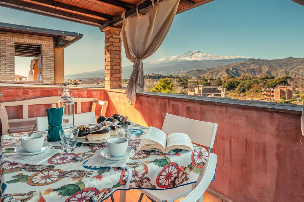 a table with a book on a balcony with a view at Mansarda Relax Wellness Gym & Spa in Taormina