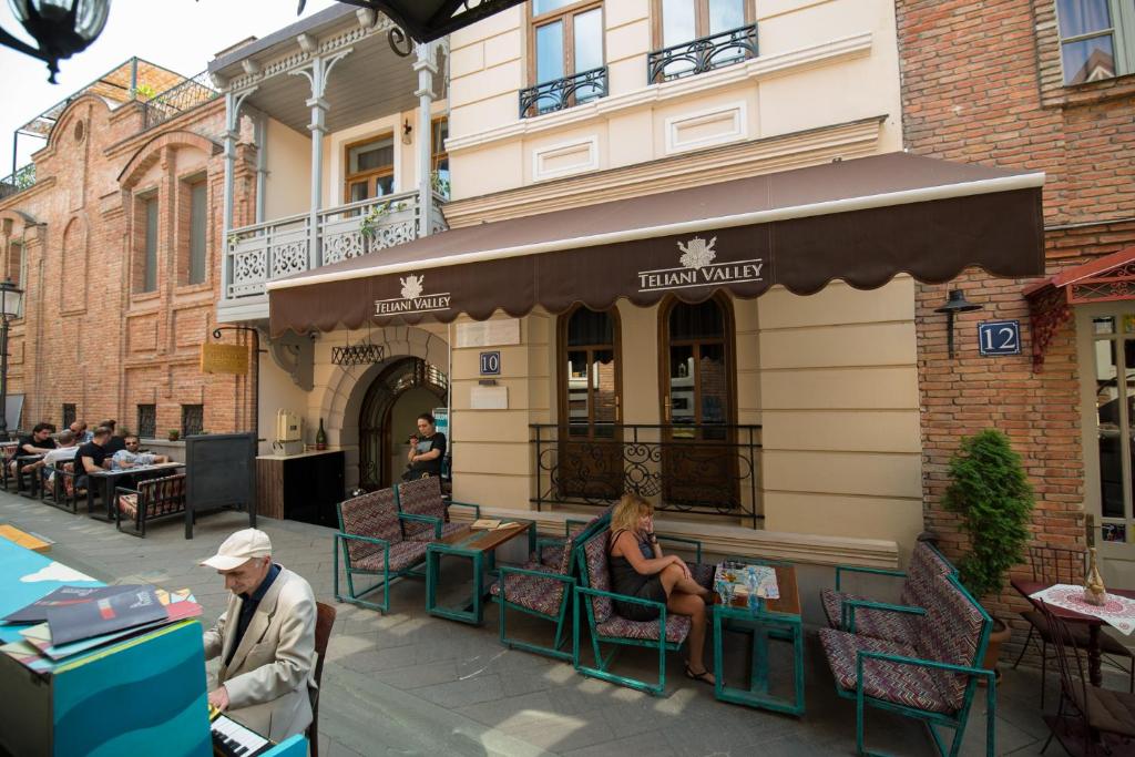 eine Gruppe von Personen, die vor einem Restaurant sitzen in der Unterkunft Hotel Opinion in Tbilisi City