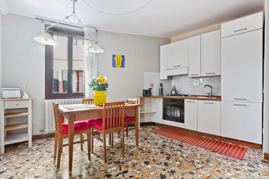 a kitchen with white cabinets and a table and chairs at Castello Cozy Apart x4 - Calle Crosera in Venice