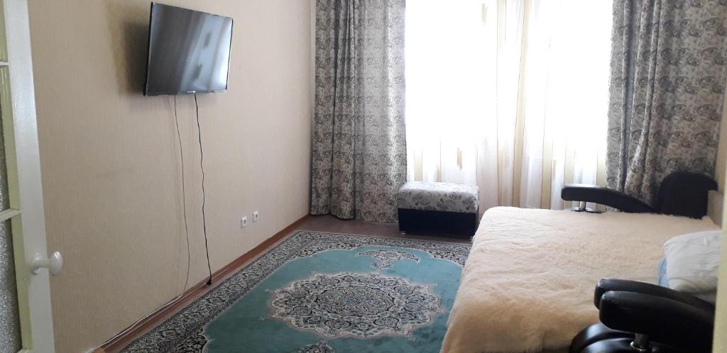 ニジネヴァルトフスクにあるApartment on Mira 94のベッド1台と壁掛けテレビが備わる客室です。