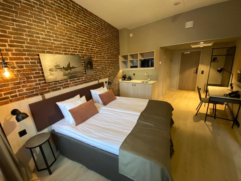 a bedroom with a large bed with a brick wall at Skyline Airport Hotel in Vantaa