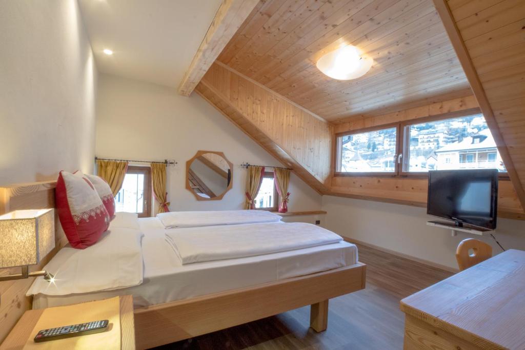 a bedroom with two beds and a flat screen tv at Hotel Garni Snaltnerhof in Ortisei