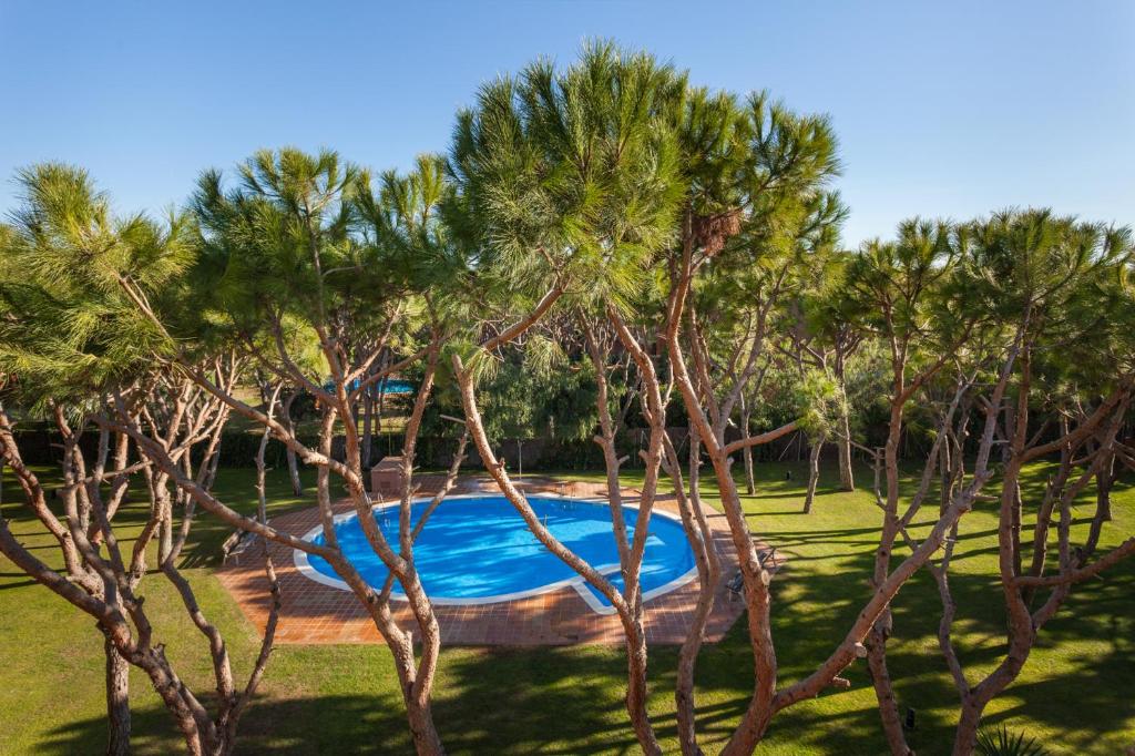 a swimming pool in a park with trees at HHBCN Beach Apartment Gava #2 in Gavà