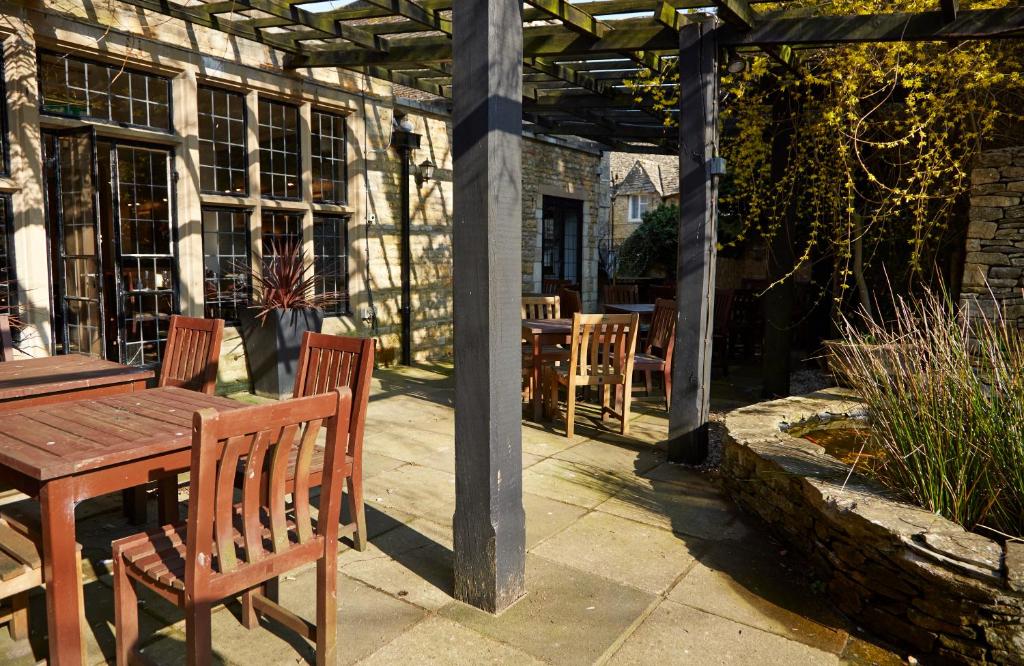 an outdoor patio with a wooden table and chairs at Old Manse Hotel by Greene King Inns in Bourton on the Water