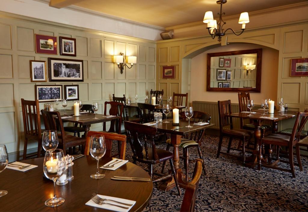 a restaurant with wooden tables and chairs and candles at Old Manse Hotel by Greene King Inns in Bourton on the Water