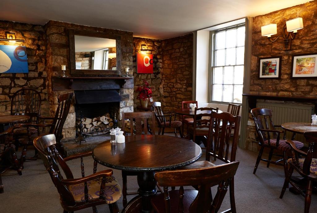 a restaurant with tables and chairs and a fireplace at Old Manse Hotel by Greene King Inns in Bourton on the Water
